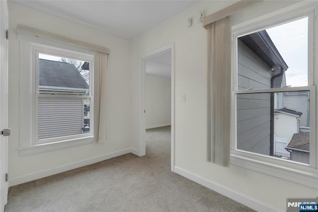 spare room featuring baseboards and light colored carpet