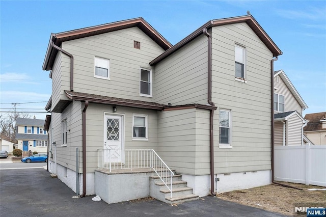 rear view of property with crawl space and fence