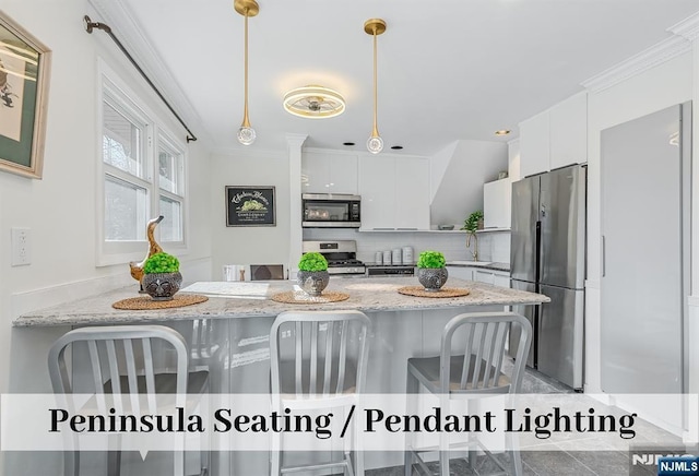 kitchen featuring pendant lighting, stainless steel appliances, backsplash, white cabinetry, and a sink