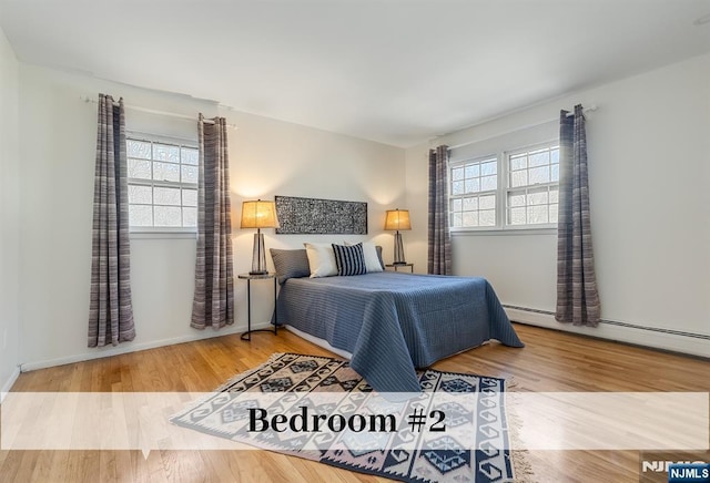 bedroom featuring a baseboard radiator, wood finished floors, and baseboards