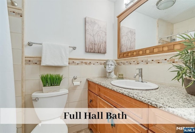 full bathroom with tile walls, vanity, toilet, and walk in shower