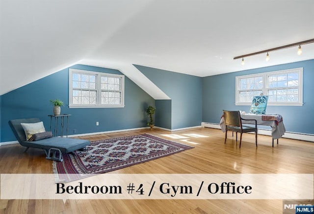 living area with wood finished floors, baseboards, vaulted ceiling, baseboard heating, and rail lighting