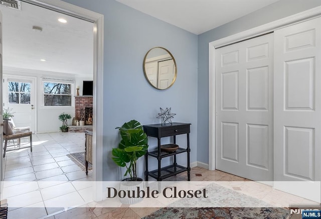 foyer with a brick fireplace, visible vents, and baseboards