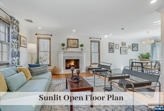 living area with recessed lighting, a fireplace, wood finished floors, visible vents, and ornamental molding