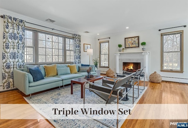 living area featuring a fireplace, visible vents, crown molding, and wood finished floors