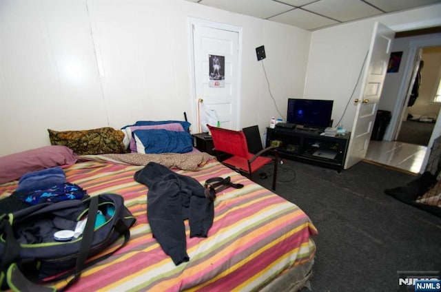 bedroom with dark colored carpet and a paneled ceiling