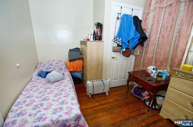 bedroom featuring baseboard heating and dark wood finished floors