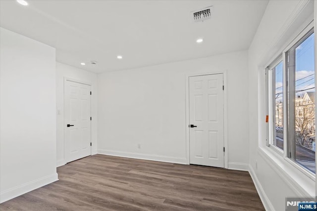 spare room with baseboards, visible vents, dark wood-type flooring, and recessed lighting