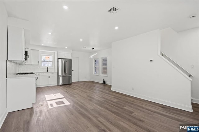 unfurnished living room featuring baseboards, visible vents, dark wood-type flooring, and recessed lighting