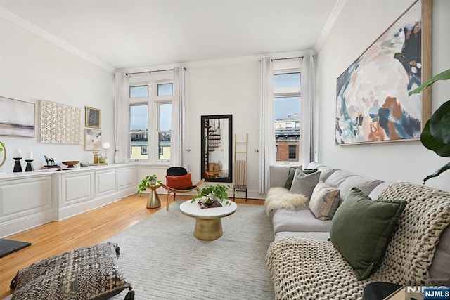 living area with a healthy amount of sunlight, wood finished floors, and crown molding