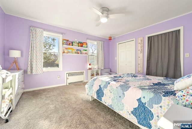 carpeted bedroom featuring radiator, baseboards, ceiling fan, ornamental molding, and two closets