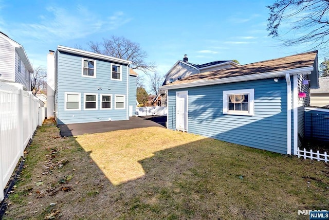 rear view of house with a yard, a patio, an outbuilding, and a fenced backyard