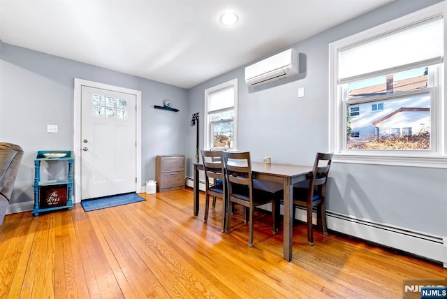 dining space with light wood-type flooring, a wall mounted AC, and baseboards