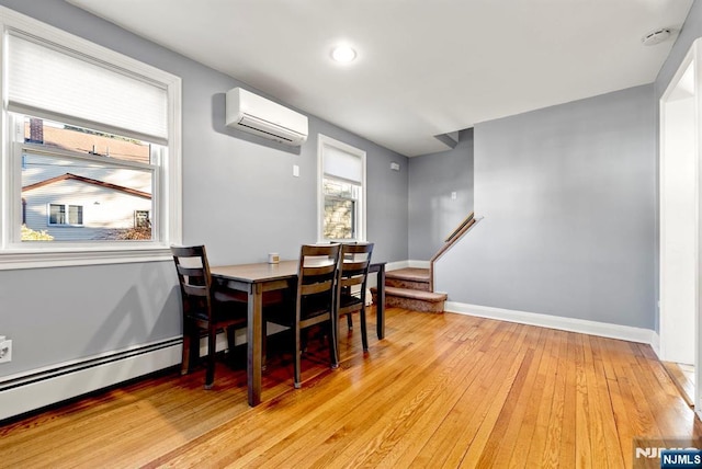 dining area featuring stairway, baseboards, an AC wall unit, and light wood-style flooring