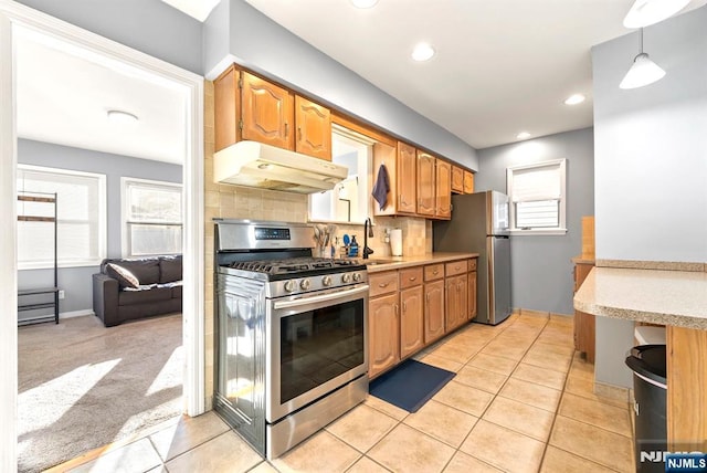 kitchen with under cabinet range hood, a sink, tasteful backsplash, appliances with stainless steel finishes, and light colored carpet