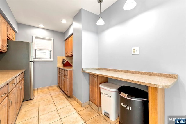 kitchen featuring pendant lighting, freestanding refrigerator, recessed lighting, light tile patterned flooring, and light countertops