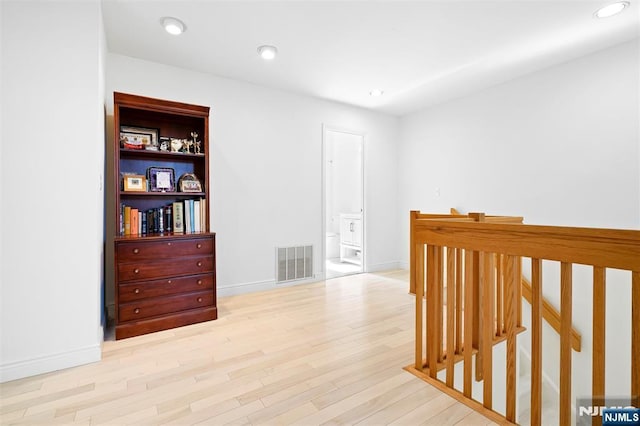 hallway with light wood-type flooring, visible vents, baseboards, and recessed lighting