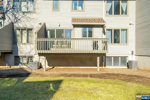 rear view of property with central AC, a shingled roof, and a lawn