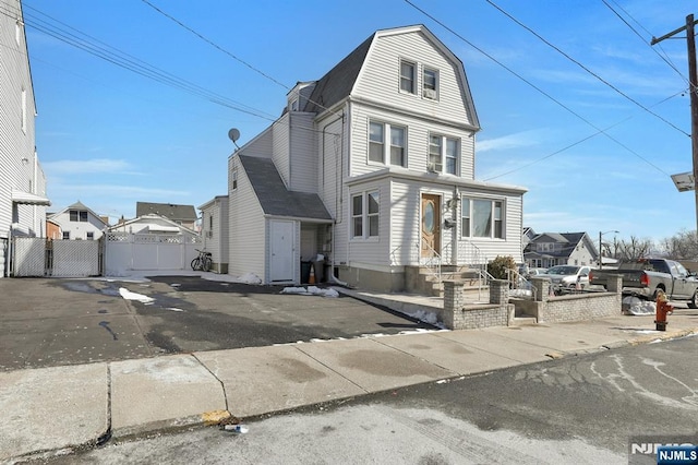 view of front of property with a gate, a residential view, fence, and a gambrel roof