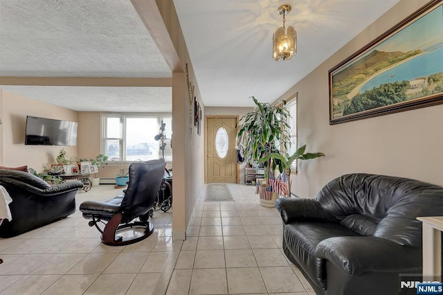 living room with light tile patterned floors, baseboard heating, and a textured ceiling