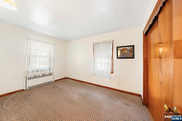 empty room featuring radiator, baseboards, and carpet floors