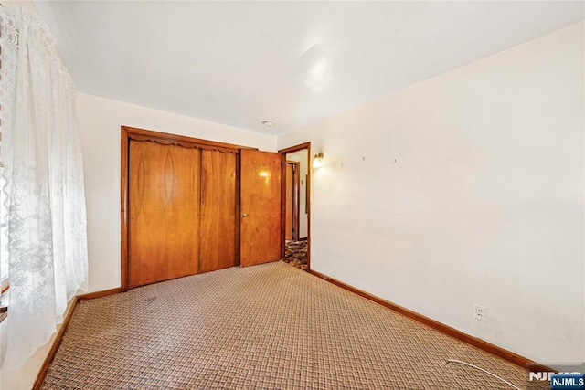 unfurnished bedroom featuring light carpet, a closet, and baseboards