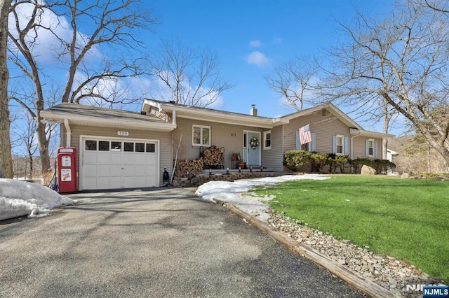 single story home with aphalt driveway, brick siding, a chimney, an attached garage, and a front yard