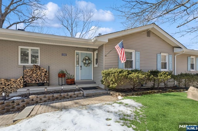 view of exterior entry with a yard and brick siding