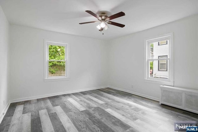 empty room featuring radiator, plenty of natural light, and wood finished floors