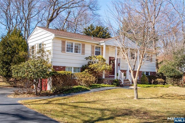 raised ranch featuring brick siding and a front yard