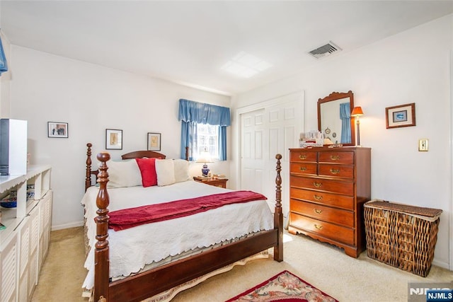 bedroom with a closet, visible vents, and light colored carpet