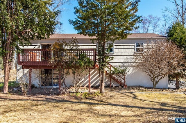 rear view of house featuring a yard, a deck, and stairs