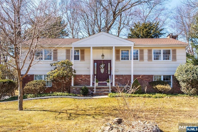 raised ranch featuring brick siding and a front lawn