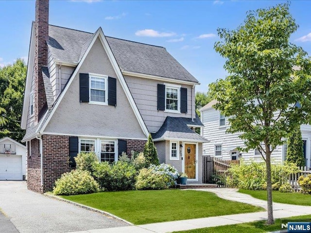 view of front of property with brick siding, a chimney, a front lawn, and fence