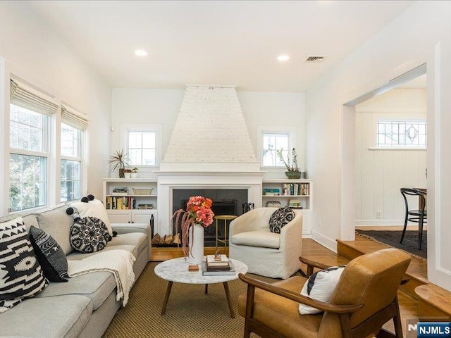 living area featuring recessed lighting, a fireplace, wood finished floors, visible vents, and baseboards