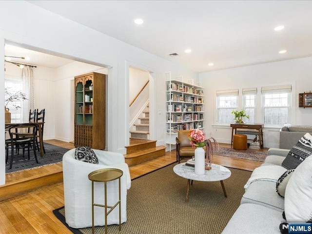 living room featuring recessed lighting, wood finished floors, visible vents, and stairs