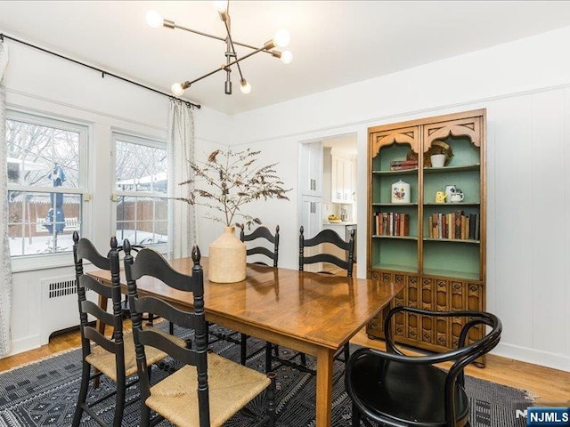 dining area with radiator, a notable chandelier, and wood finished floors