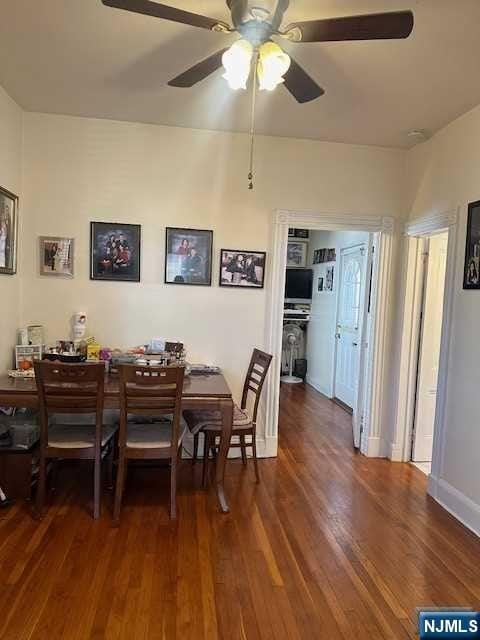 dining space with ceiling fan, dark wood-type flooring, and baseboards