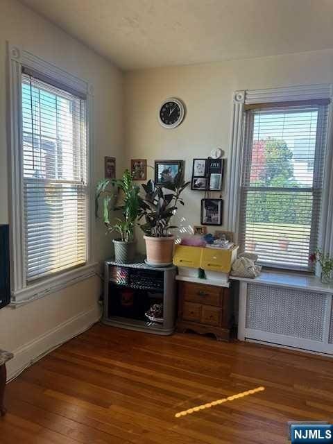 office space featuring radiator heating unit, baseboards, and dark wood finished floors