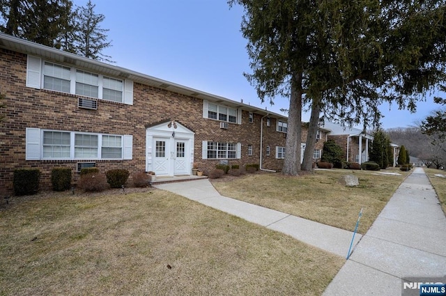 townhome / multi-family property featuring a front yard and brick siding