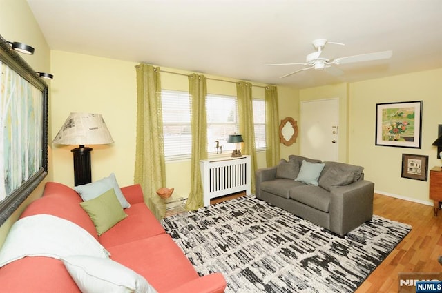 living room featuring wood finished floors, a ceiling fan, and baseboards