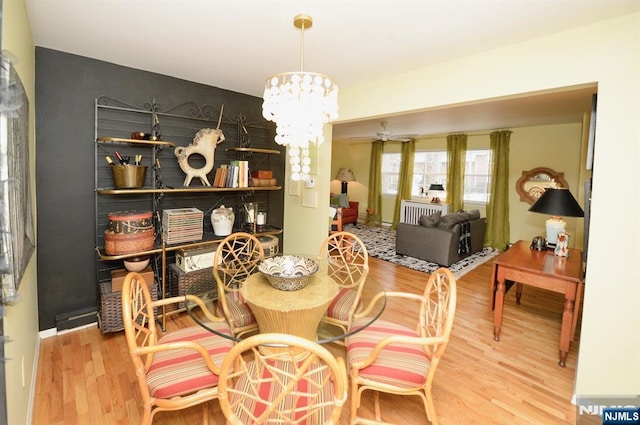 dining room with ceiling fan with notable chandelier and wood finished floors