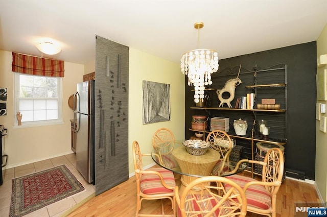 dining space featuring baseboards, wood finished floors, and a notable chandelier