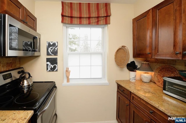 kitchen featuring stainless steel appliances, light stone counters, and tasteful backsplash