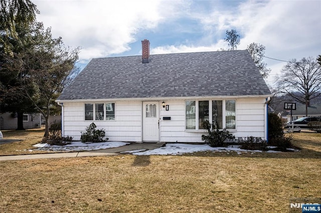 view of front of house featuring a front lawn, roof with shingles, and a chimney