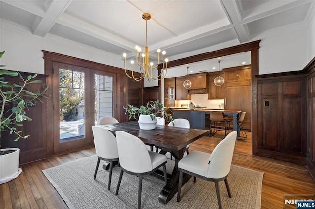 dining space featuring light wood-style flooring, coffered ceiling, and beam ceiling