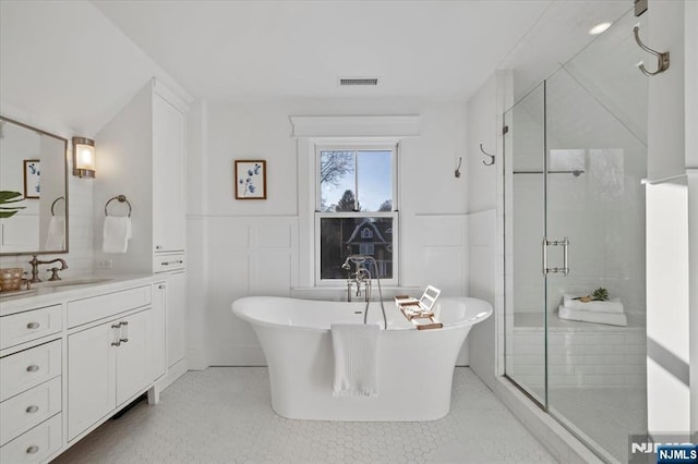 full bathroom with a stall shower, visible vents, a soaking tub, vanity, and tile walls