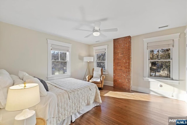 bedroom with a ceiling fan, baseboards, visible vents, and wood finished floors