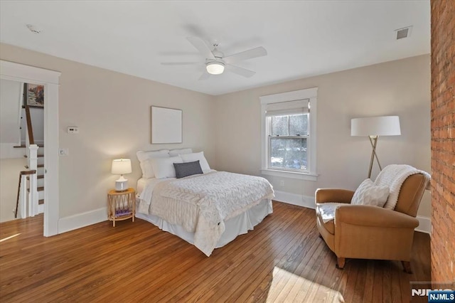 bedroom with a ceiling fan, baseboards, visible vents, and wood finished floors