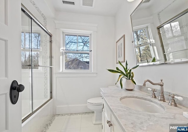 bathroom featuring a healthy amount of sunlight, vanity, baseboards, and bath / shower combo with glass door